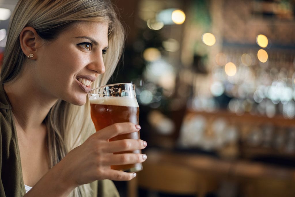 woman drinking beer in bar showing Signs of Alcoholism and day drinking
