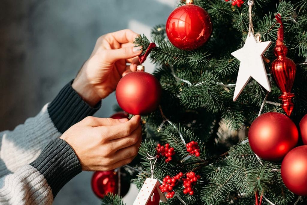 A woman hangs ornaments on a tree as she enjoys sober holidays