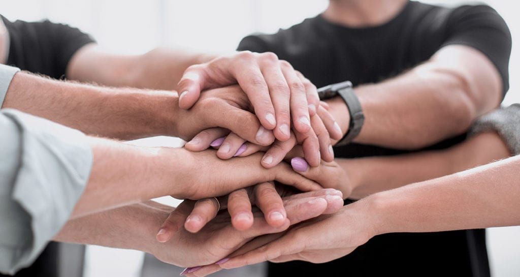 a group of people put their hands on top of each other and talk about the benefits of group therapy