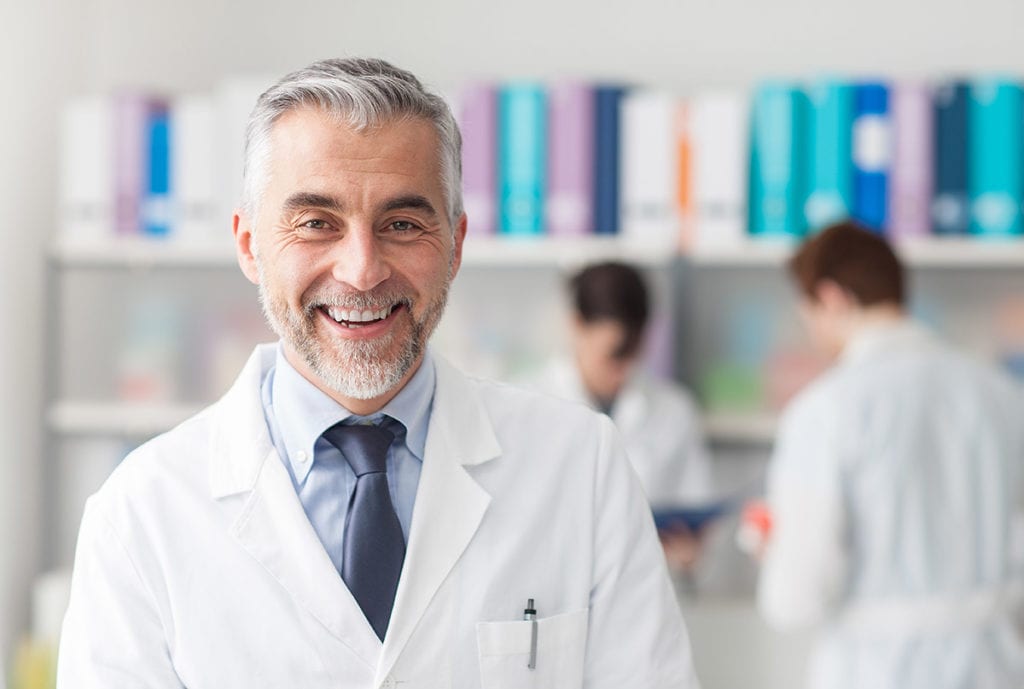 a doctor smiles as doctors behind him research oxycodone vs hydrocodone