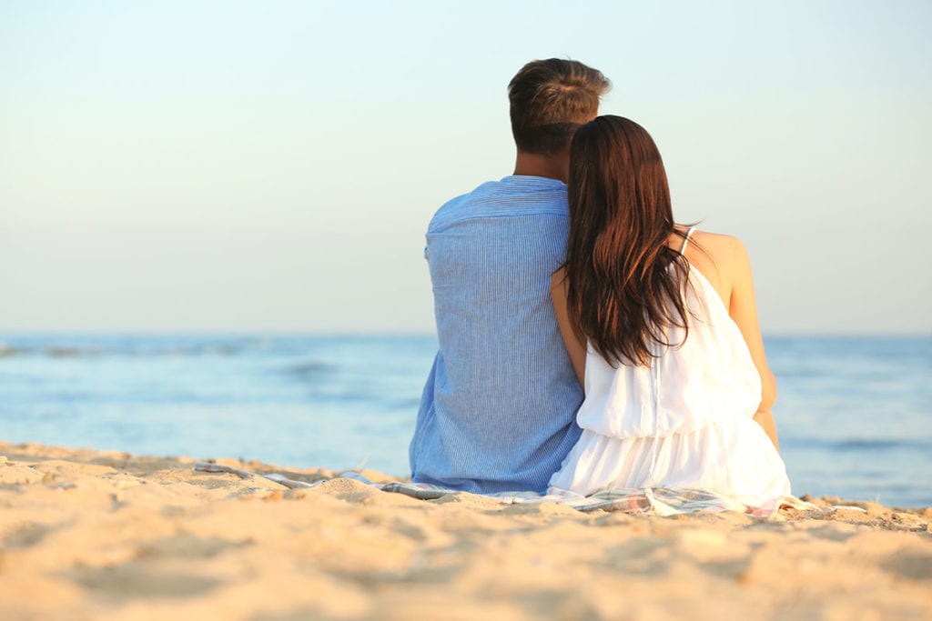 woman leaning on man at the beach wondering Is My Loved One an Alcoholic
