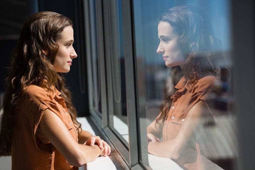 woman staring out window showing Signs of Depression