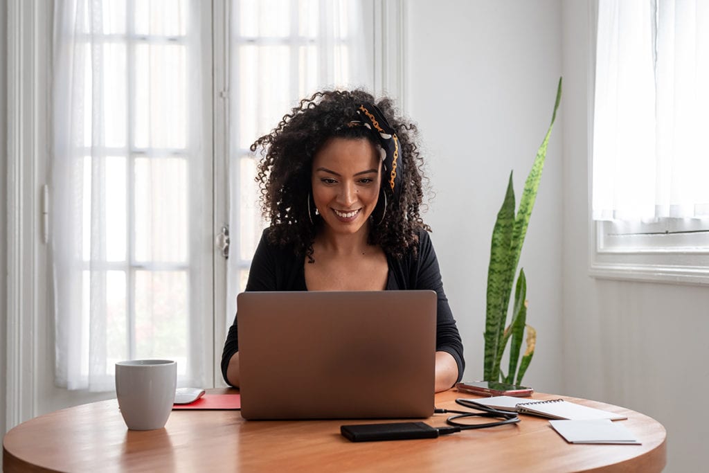 smiling woman using laptop for online services for Coping with Isolation During Coronavirus