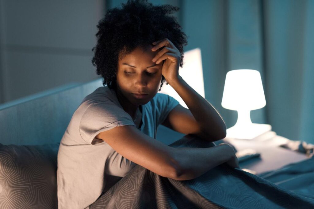 Woman sits up in bed, as she struggles with signs of benzo abuse