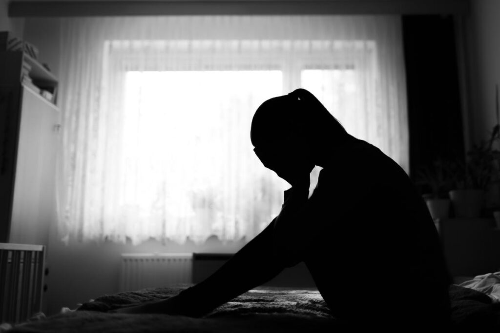 Woman sits in the dark, worrying about mental health and addiction