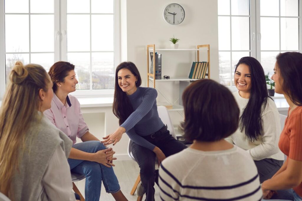 Women chat and bond in group therapy, learning the benefits of a women's rehab program