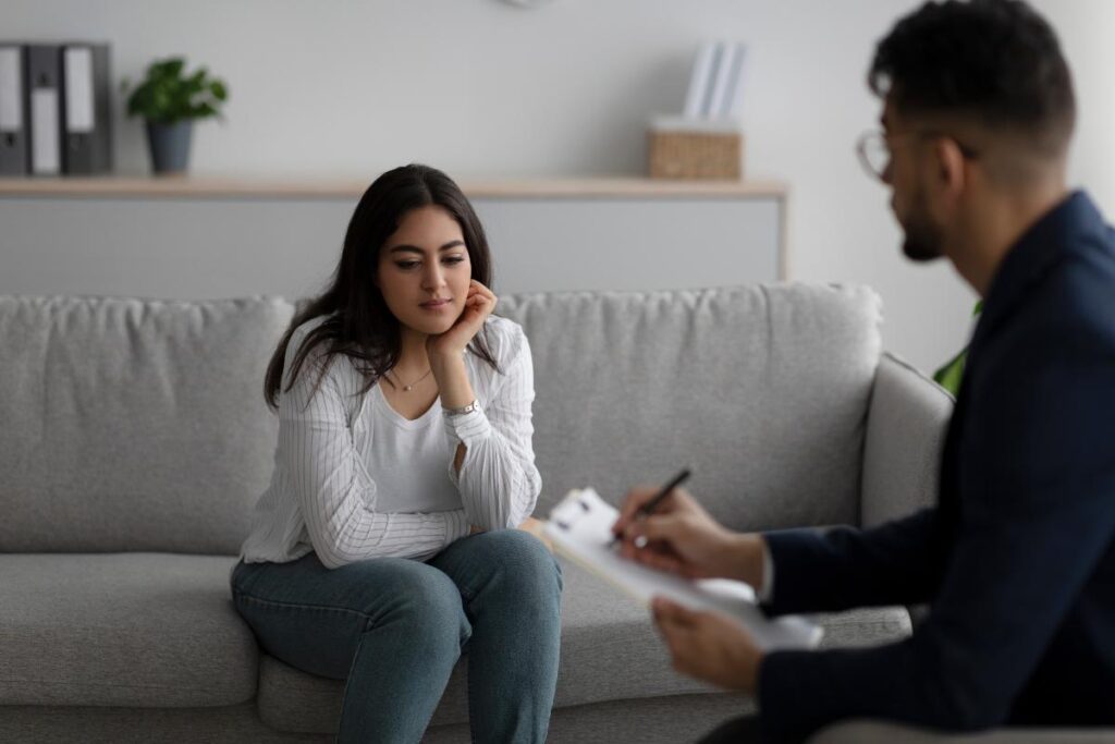 Woman sits on the couch as health professional explains to her the benefits of inpatient addiction treatment