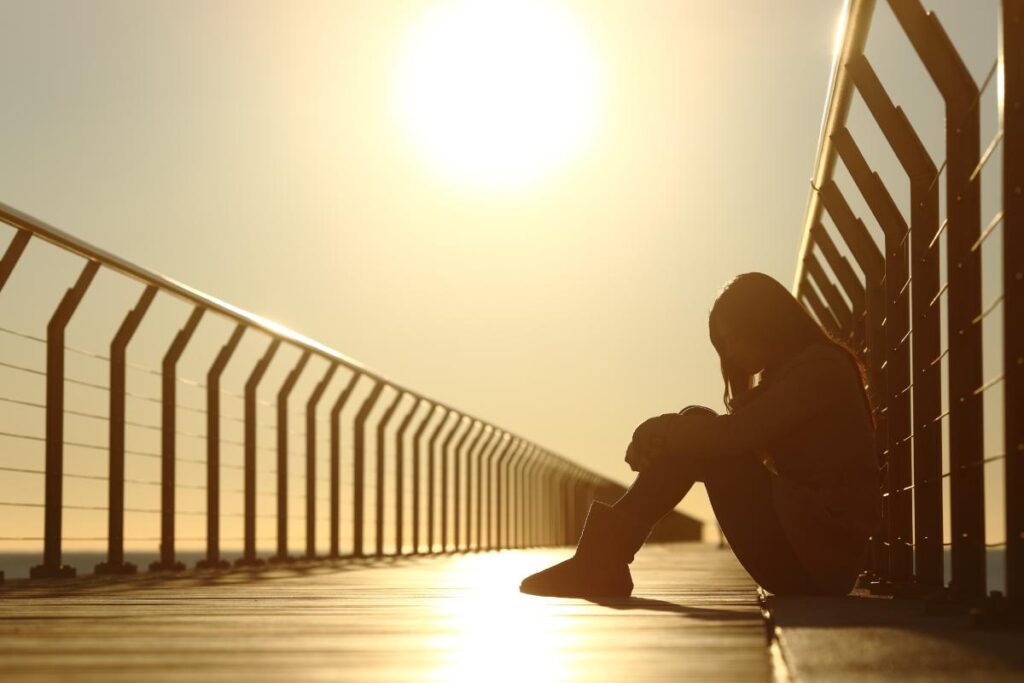 Person sits on bridge in agony, as they deal with the dangers of cocaine use