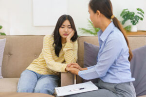 Sad woman holds hands with therapist in trauma therapy program