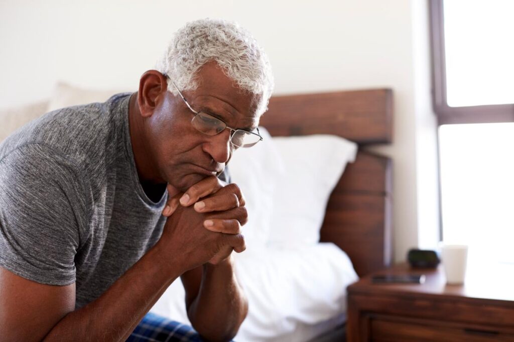 A person prays by their bedside thinking about their alcohol dependence