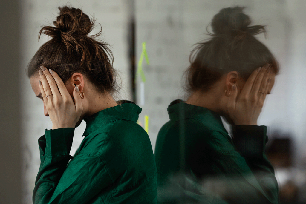 Woman leans against wall as she struggles wtih self-medicating with alcohol